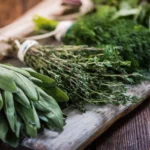 Fresh bundles of sage, thyme, and dill on a rustic wooden board, showcasing herbs for everyday cooking.