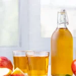 Bottle of apple cider vinegar with fresh apples, perfect for making vinegar tinctures.