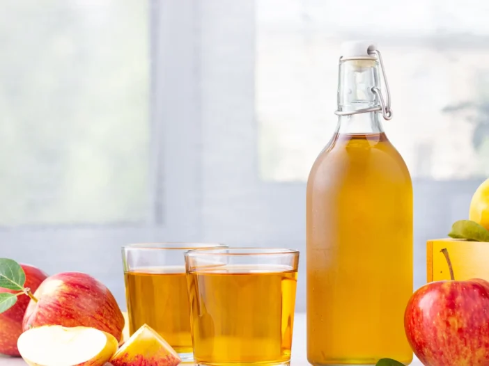 Bottle of apple cider vinegar with fresh apples, perfect for making vinegar tinctures.