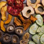 Assorted freeze-dried and dehydrated fruits and vegetables on a wooden surface.